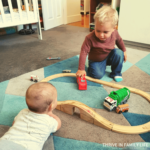 two brothers baby and toddler playing with wooden train set montessori at home multiple children