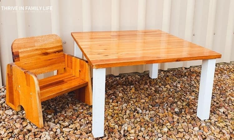 DIY Weaning Table and DIY Weaning Chair on tan gravel in front of tan shed. 