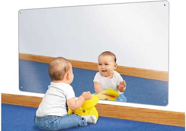 infant sitting in front of a medium sized infant montessori mirror